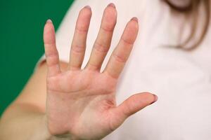 Blurred portrait of young lady extending hand forward saying no enough. Focus on female palm close up raised in prohibiting gesture. shows stop sign prohibition symbol keeps palm forward to camera. photo