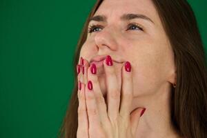 Portrait of afraid screaming young woman different emotions of a young girl on a green background chromakey beautiful facial features real people pink T-shirt white skinned. European photo