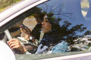 Two Muslim women wearing hijab converse on a smartphone while traveling together in a car through the photo