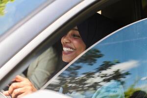 Two Muslim women wearing hijab converse on a smartphone while traveling together in a car through the photo