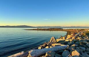 sunset on the Ocean Calmness calm sea on Vancouver Island resting in trailers on the shore bright colors of dark blue orange stripe on the horizon from the sun rich space for text travel advertising photo