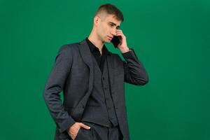 business man talking on a mobile phone in a black suit. emotions of a handsome man guy on a green background chromakey close-up dark hair young man. phone in hand talk dial SMS online call gadget boss photo