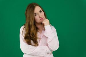 Concept portrait for the waist of a pretty girl, a young woman with long beautiful brown hair and a black jacket and jeans on a green background. In studio in different poses showing emotions. photo