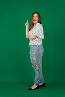 young woman in a white T-shirt in jeans in full growth on a grren background photo