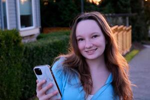 Perky female teenager texting in the park with smart phone photo