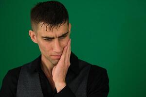 Tooth ache concept. Indoor shot of young male feeling pain, holding his cheek with hand, suffering from bad toothache, looking at camera with painful expression photo
