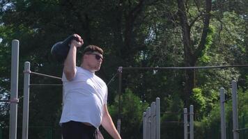 Esportes e lazer. Forte caucasiano homem trabalhando Fora usando kettlebell dentro a parque video