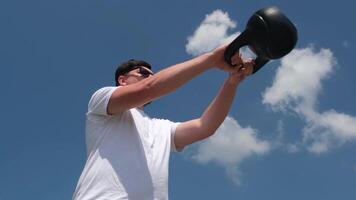 Esportes e lazer. Forte caucasiano homem trabalhando Fora usando kettlebell dentro a parque video