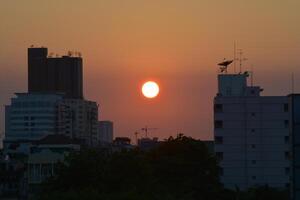 Bangkok, Thailand - April 28, 2024, A view of the sunset among tall buildings in a big city in the summer of Thailand. photo