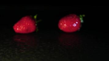 de hand- zet aardbeien Aan de nat oppervlakte in de donker. detailopname video