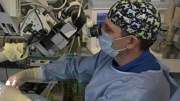 kirurg man i särskild kläder gör mikroskopisk kirurgi på ent organ använder sig av en kirurgisk mikroskop.innovativ teknik i medicin video