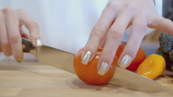 The girl cuts tomatoes. ACTION. The cook is cutting tomatoes. Red tomatoes are cut with a knife. Vegetables are cut on a wooden board video