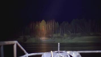 View of the night coast with trees. CLIP View from the boat to the trees. Part of a white boat in the frame against the background of the night sky video