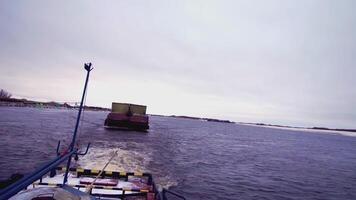 The barge pulls the cargo in the frame. clip. A cargo barge with a trailer floats on the water. A cargo ship is moving along the river. Trees in the background video