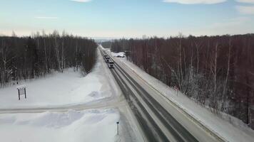 superiore Visualizza di il inverno strada su quale macchine e camion viaggio. scena. il cielo e terra siamo blu a partire dal neve. il traccia per macchine bugie attraverso cumuli di neve. Visualizza a partire dal il quadcopter a partire dal sopra su il traccia video