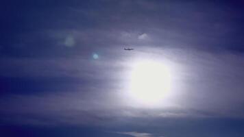 Bottom view of flying plane on background of bright sun. Creative. Beautiful blue sky with bright sun and flying plane. Flying plane in clear sunny sky video