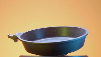 Black frying pan on an orange background. ACTION. Frying pan advertisement on a plain background. A spinning frying pan on a red background. video