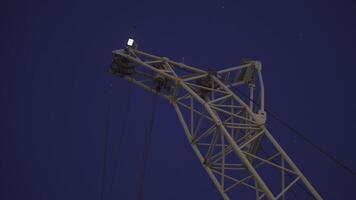 Cargo crane in the frame. clip. In the dark, the white parts of the crane glow against the dark sky. Loading crane working in the evening video