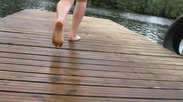 een Mens loopt en springt in de water van de dijk. creatief. een Mens langzaam loopt naar de vijver naar zwemmen. een vent in shorts rennen en vallen in de water van de rivier- video