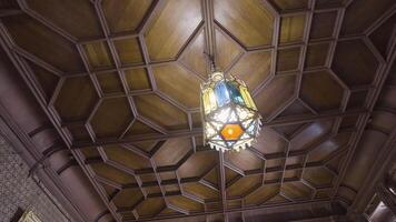 Bottom view of a wooden beautiful old fashioned ceiling with a hanging chandelier made of stained glass. Action. Details of a retro stylized room or a museum. video