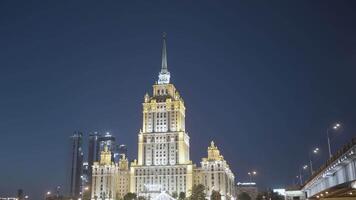 Late night cityscape with illuminated skyscraper in Moscow designed in the Stalinist style. Action. Beautiful building on a dark blue evening sky background, concept of architecture. video