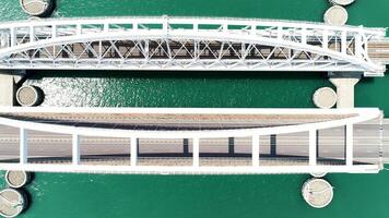 Top view of big bridge over green river. Action. Big white bridge with highway and traveling cars. Beautiful turquoise river with highway on bridge video