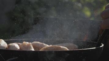 Pies in a pan. Creative. The dough is fried in a hot pan. The oil is boiling. Frying food in nature on an open fire video