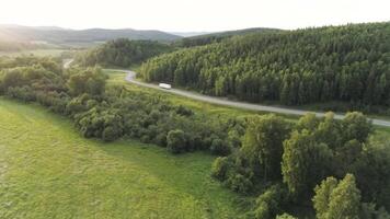 Top view of beautiful green landscape with truck driving along highway. Scene. Panorama of green trees with country road in summer. Summer landscape with road and sense of traveling by car video