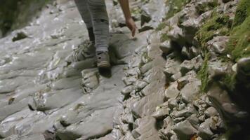 das Tourist klettert oben das Stein Weg. kreativ. Prost Aussicht von das Beine von ein Tourist Wer klettert oben das Stein Grat. Beine von ein Mädchen im Hose und Schuhe gehen oben video