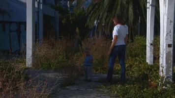 Woman follows child on walk in summer. Creative. Woman stands with child and watches him on walk. Woman walks with child in nature in summer in sunny day video