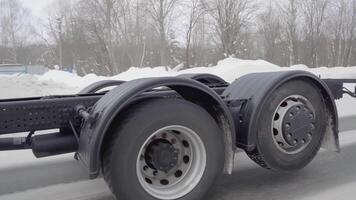 RUSSIA, MOSCOW - MARCH 21, 2022. A huge white truck is driving along the road. SCENE. Black wheels Kamaz close-up. White truck rides on the road in winter. A lot of truck wheels are shown in the frame video