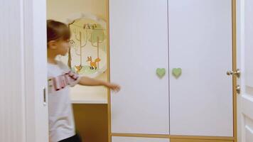 Rear view of a girl opening a white wardrobe with green handles and choosing clothes. Creative. Child taking jacket. video