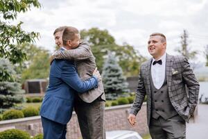 Three men in suits are hugging each other, with one man wearing a tie photo
