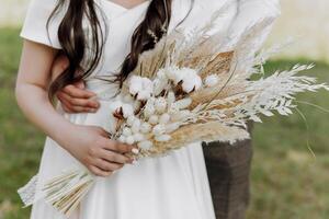 A bride and groom are posing for a picture with a bouquet of white flowers photo