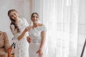 Two women are posing for a picture in a room with a chair and a potted plant photo