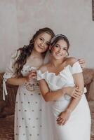 Two women are posing for a picture, one of them wearing a wedding dress photo