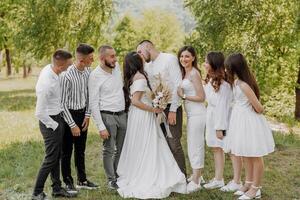A group of people are gathered in a field, with a bride and groom in the center photo