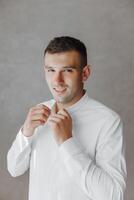 A man in a white shirt is getting ready to go out photo