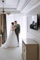 A bride and groom are standing in front of a large mirror photo