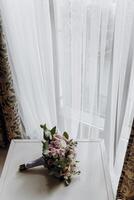 A bouquet of flowers sits on a table next to a window photo