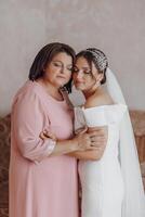 A mother hugs her daughter, the bride, wearing a wedding dress photo