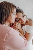 A mother hugs her daughter, the bride, wearing a wedding dress photo