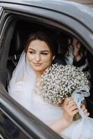 A bride is sitting in a car with a bouquet of white flowers photo