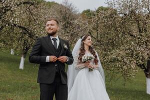 A bride and groom stand in a field of blossoming trees photo