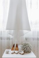 A pair of white shoes and a bouquet of white flowers are displayed on a table photo