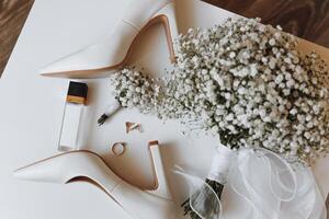 A pair of white shoes and a bouquet of white flowers sit on a table photo