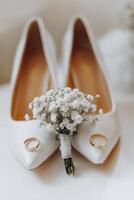 A pair of white shoes with a boutonniere of white flowers photo