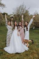 four girls are having fun in nature. The bride, surrounded by her friends, is happy in the spring garden photo