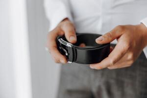 A man is holding a black belt in his hand photo