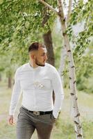 A man in a white shirt and gray pants is walking through a forest photo